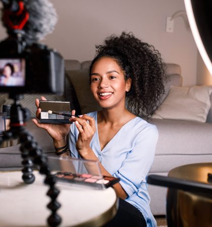 Smiling woman holding a makeup palette while recording her video